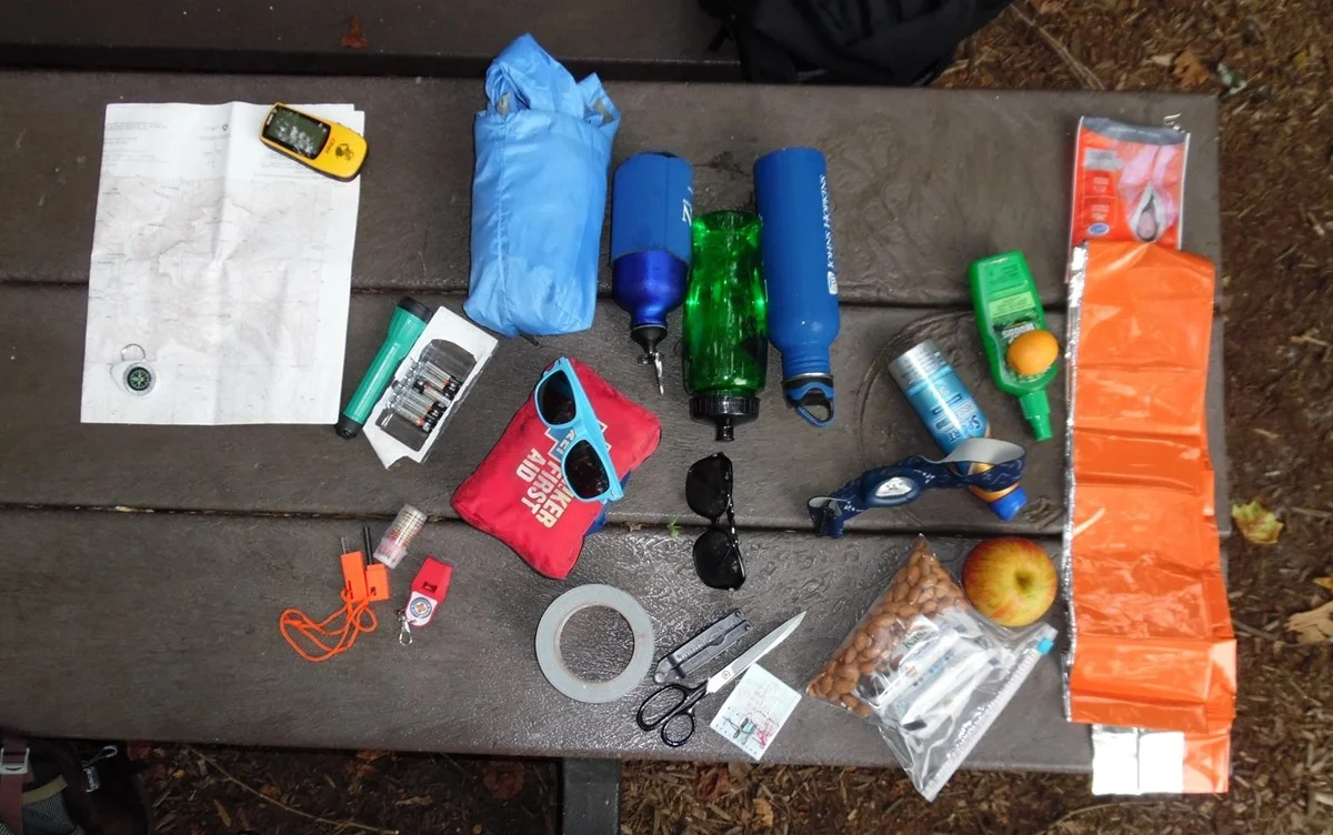 overhead photo of essential hiking gear laid out on a picnic table