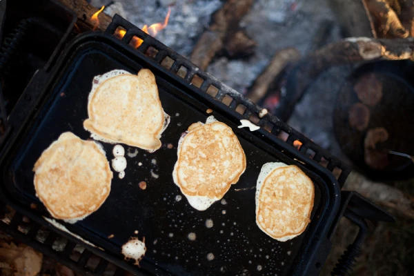 pancakes cooking on a cast iron griddle outdoors