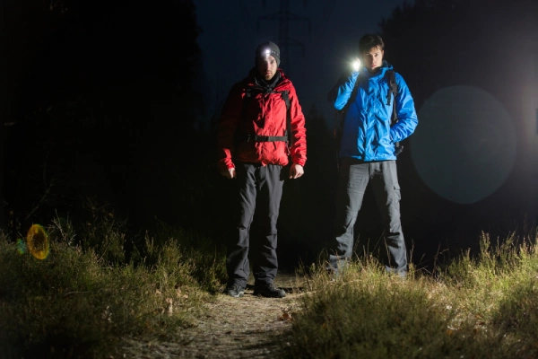 two male hikers at night shining flashlight toward viewport