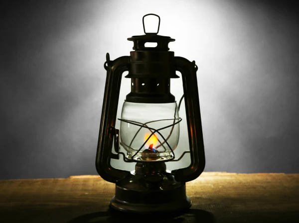 dark photo of a kerosene lamp lighting up the grey background