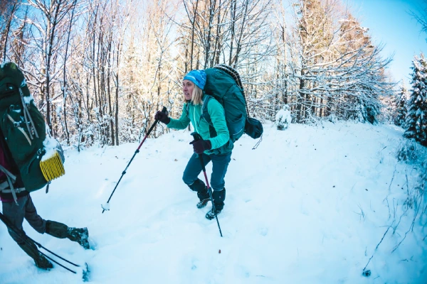 blonde women hiking in snow with heavy backpack