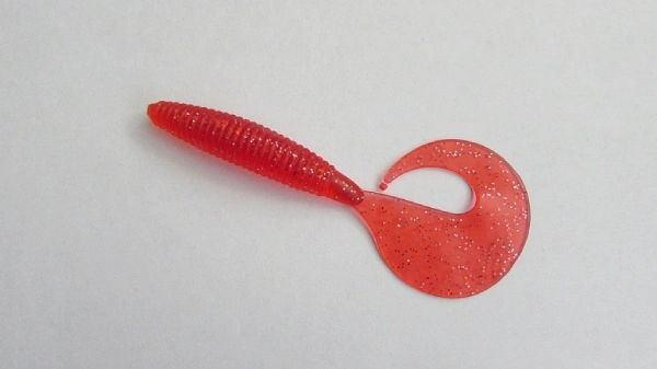 Photo of a red colored soft plastic fishing lure with grey background