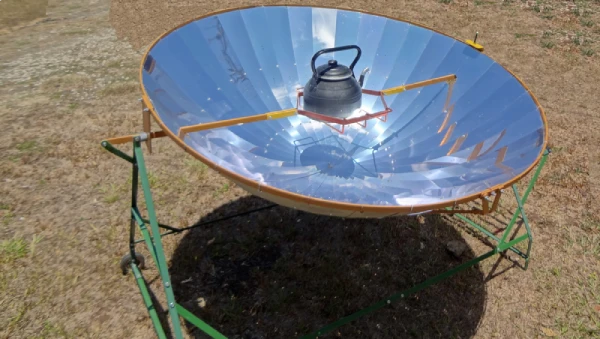 kettle on top of a dish style solar camp stove in sunlight