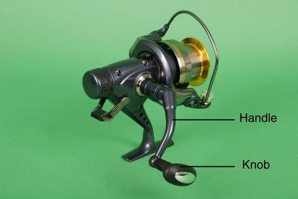 closeup image of spinning fishing reel with handle and knob labelled