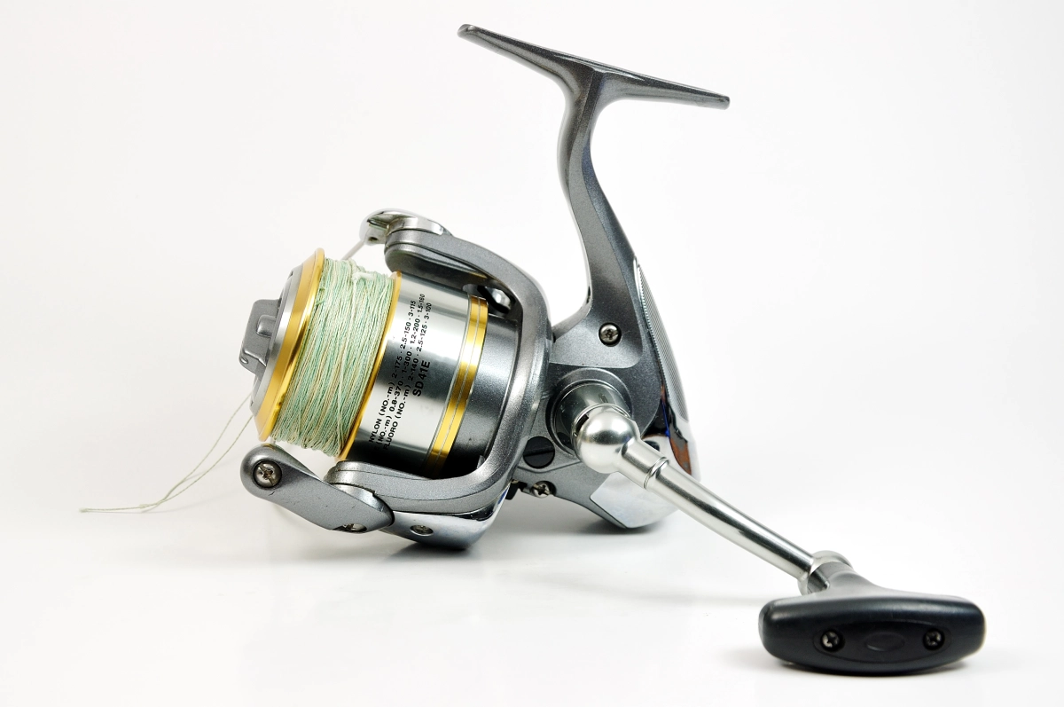 a gold and silver spin style fishing reel on a white background