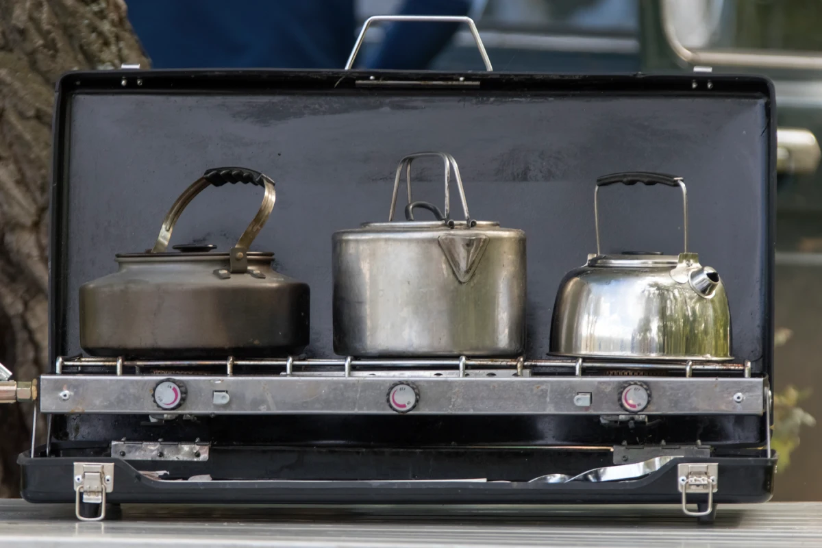 three steel pots on a black camp stove