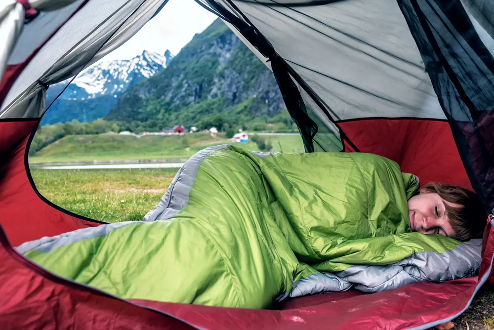 woman sleeping on her side in a green sleeping bag