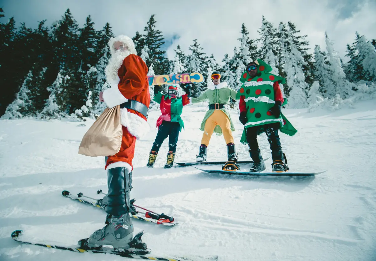 Santa and three elves riding snowboards for holiday gift guide