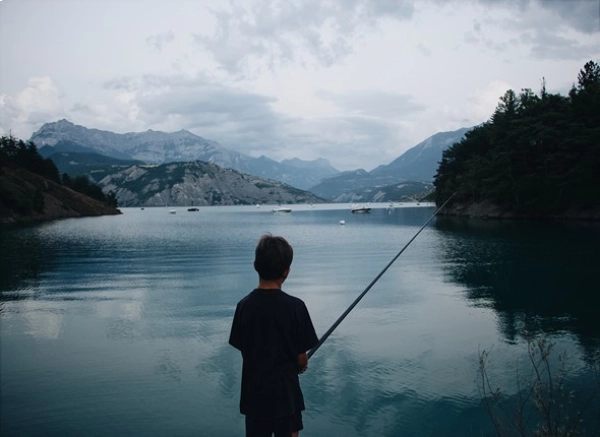 dark view from behind of a boy fishing on a grey winter day