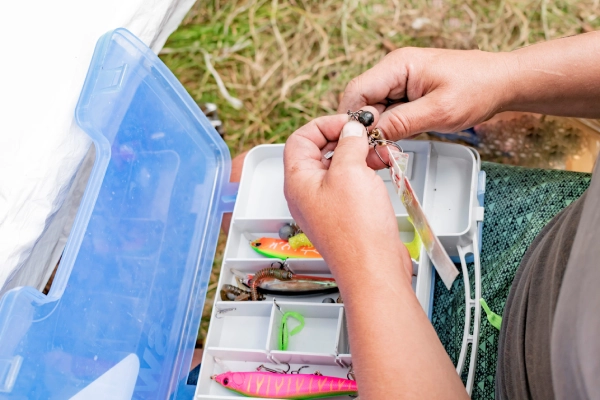 person's hand holding tackle above a full tackle box