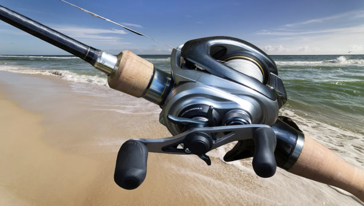 selective image of a baitcasting reel and rod in front of a coastal background