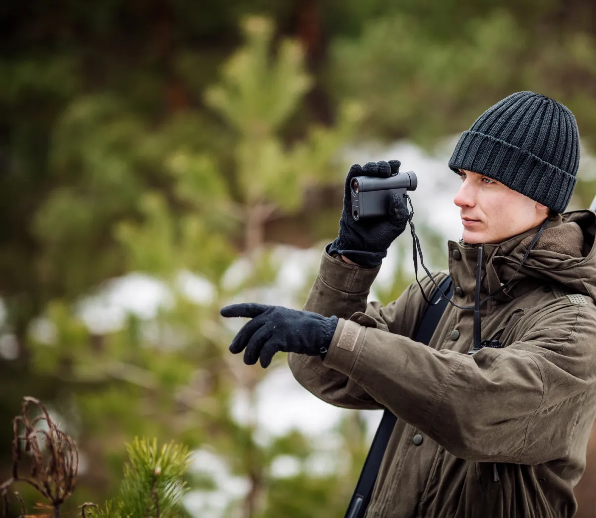 male hunter holding rangefinder pointing his finger outward